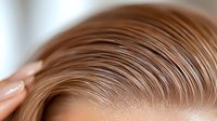 Close up view of light brown hair styled in waves showing professional hairdressing technique and natural shine on blurred background.