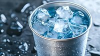 Refreshing ice cubes in metal cup with water droplets on dark background, perfect for beverage advertising and summer drink concepts.