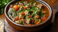 Hearty beef stew with tender meat, carrots, and fresh herbs in rich broth served in rustic ceramic bowl. Comfort food for cold weather dining and cooking content.