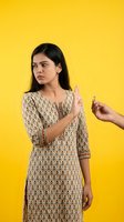 Young South Asian woman refusing cigarette with stop gesture on bright yellow background for anti-smoking health awareness campaigns.