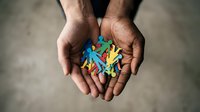 Hands holding colorful paper cutout figures representing diversity, inclusion, community support and teamwork concepts for social campaigns.