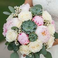 Bridal bouquet with white roses, pink peonies and green succulents held by bride in wedding dress for romantic ceremony and floral arrangements.