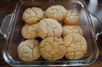 Fresh baked sugar cookies with crackled tops arranged in glass baking dish, showing classic homestyle texture and golden brown edges. Ideal for food blogs.