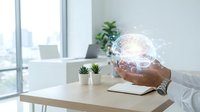 Professional businessman holding glowing digital brain hologram in modern office workspace representing artificial intelligence and innovation technology.