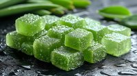 Green jelly candies with sugar coating on dark stone background with fresh herbs. Sweet dessert confectionery closeup macro photography.