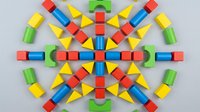 Colorful wooden building blocks arranged in symmetrical geometric pattern on white background, isolated for design, educational materials, and creative projects.