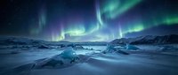 Spectacular aurora borealis dancing over frozen Arctic landscape with ice formations and snow-covered terrain under starry night sky for nature photography.