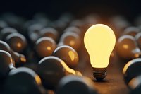 Glowing light bulb standing out among unlit bulbs, symbolizing innovation, bright idea, and creative thinking in business concept.