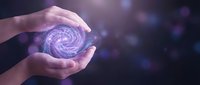 Hands holding glowing purple spiral galaxy orb with particle effects and bokeh light, representing energy, innovation, and cosmic power for technology and science concepts.