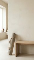 Minimalist interior with rolled fabric leaning against cream wall, wooden bench, and natural light from window. Suitable for home decor, design inspiration, and lifestyle content.