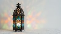 Ornate lantern with colorful stained glass panels casting vibrant light patterns on white surface, creating warm and cool tones for home decor and lighting design projects.