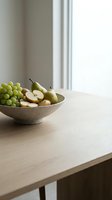 Fresh green grapes and sliced pears arranged in a concrete bowl on a wooden table near a bright window, perfect for food styling and home decor projects.