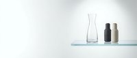 Minimalist glass shelf with transparent vase and ceramic bottles against white wall. Modern home decor and interior design styling concept.