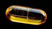 Transparent amber capsule with golden liquid and sparkling particles inside, isolated on black background for pharmaceutical or supplement marketing.