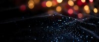 Sparkling black surface with glittering particles and warm bokeh lights creating magical atmosphere for luxury design projects and festive backgrounds.