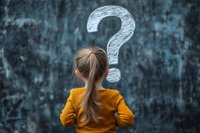 Young girl in yellow sweater looking at large question mark on dark textured wall, back view, concept of childhood curiosity and learning.