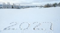 2024 written in footprints across snowy winter landscape with forest and mountains in background, aerial view for New Year greeting cards and seasonal marketing campaigns.