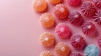 Colorful fruit jelly candies arranged in diagonal pattern on pink background, top view. Sweet gummy confectionery with citrus shape and sugar coating.