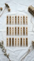 Natural wooden clothespins arranged in rows on white fabric with dried flowers and jute twine for rustic crafting and home organization projects.