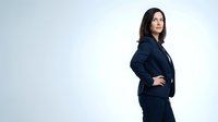 Young woman with long dark hair and olive complexion wearing a navy business suit, standing in confident pose with hand on hip against white background, suitable for corporate and professional business applications.