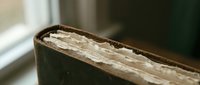 Vintage leather book spine with worn gilded pages showing age and character, close-up detail of antique literature binding for educational or literary projects.