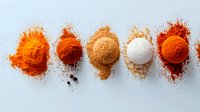 Vibrant colorful spice piles arranged in row on white background including turmeric, paprika, cinnamon, salt and chili powder for cooking and seasoning.