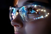 Close up view of eyeglasses reflecting digital technology interface with blue circuit patterns and glowing lights against dark background, modern cybersecurity concept.