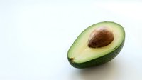 Fresh ripe avocado half with pit on white background, healthy organic fruit for cooking, nutrition and diet concepts, isolated food ingredient.