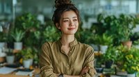 Young Asian woman entrepreneur smiling confidently in modern greenhouse office with plants, sustainable business concept for eco-friendly startup ventures.
