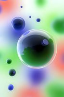 Translucent bubbles floating against colorful blurred background with blue and green spheres creating abstract composition for modern design projects.