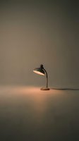 Vintage desk lamp with warm glow illuminating neutral surface, casting soft shadows. Minimalist lighting setup for interior design, home decor, and workspace styling projects.