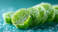 Fresh sliced green jalapeño peppers with salt crystals and water drops in macro photography on turquoise background, selective focus for food design.
