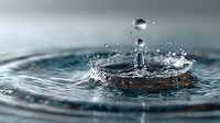 Water drop creating splash with ripples and crown formation in clear liquid surface captured in high-speed macro photography for nature and science concepts.