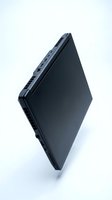 Sleek black laptop closed and balanced on edge, isolated on white background, showcasing slim profile, ventilation grilles, and USB ports.