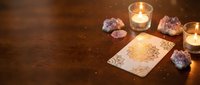 Mystical tarot card reading setup with burning candles and amethyst crystals on wooden table creating atmospheric spiritual divination scene for fortune telling.