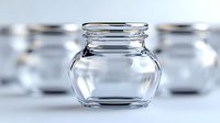 Empty glass jar with curved shape and threaded rim on blurred background of similar containers, suitable for food storage or crafting projects.