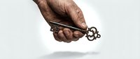 Elderly hand holding ornate vintage key with decorative handle against white background. Concept of unlocking secrets, wisdom, heritage and solutions.