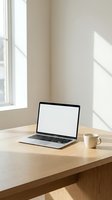 Modern laptop with blank white screen and coffee mug on wooden desk near window with natural sunlight for remote work and productivity mockup.