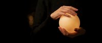 Hands gently cupping glowing orb of light in darkness, symbolizing protection, care, energy, and spiritual guidance for wellness and meditation concepts.
