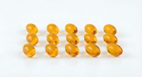 Golden amber vitamin E capsules arranged in neat rows on white background for health and wellness supplement marketing materials.