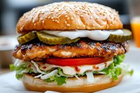 Grilled chicken burger with fresh vegetables, pickles, mayo sauce and sesame seed bun in close up view, appetizing fast food photography for menu and advertising.