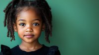 Smiling African American girl with natural curly hair wearing black dress against green background, portrait in studio lighting with copy space.
