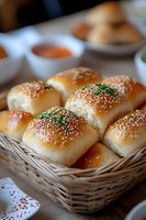 Fresh baked dinner rolls with sesame and herbs in wicker basket, golden brown crust and soft texture, served with dipping sauces for appetizer.