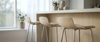 Modern bar stools with curved seats and metal legs positioned at wooden counter in bright, minimalist kitchen with natural light and potted plants.