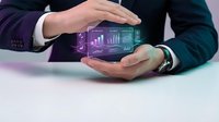 Businessman in formal suit holding smartphone displaying colorful holographic data analytics charts and graphs for business intelligence and financial reporting applications.