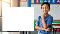 Young Asian boy student holding blank white board in colorful classroom setting for educational presentations and school projects.