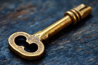 Vintage brass skeleton key with ornate design lying on dark textured surface, dramatic lighting highlights antique metalwork details and worn patina finish.