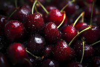Fresh dark red cherries with water droplets on their glossy surface, creating a juicy and appetizing appearance for food photography and culinary use.