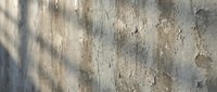 Weathered concrete wall with peeling paint and natural aging texture showing urban decay and industrial surface deterioration for architectural backgrounds.
