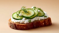 Fresh cucumber slices with creamy spread and herbs on artisan bread slice, healthy breakfast or appetizer concept for culinary photography and food styling.
